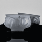 Close-up of relief glaze glass tea cup showing serpent scale texture and carved ebony coaster detail