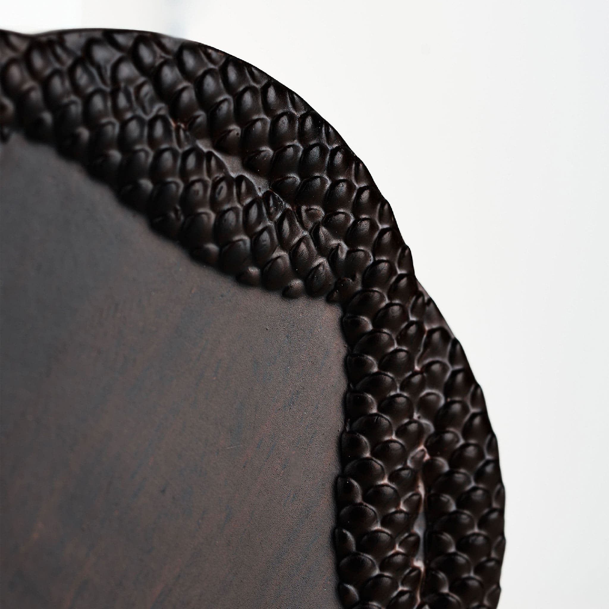 Close-up of relief glaze glass tea cup showing serpent scale texture and carved ebony coaster detail