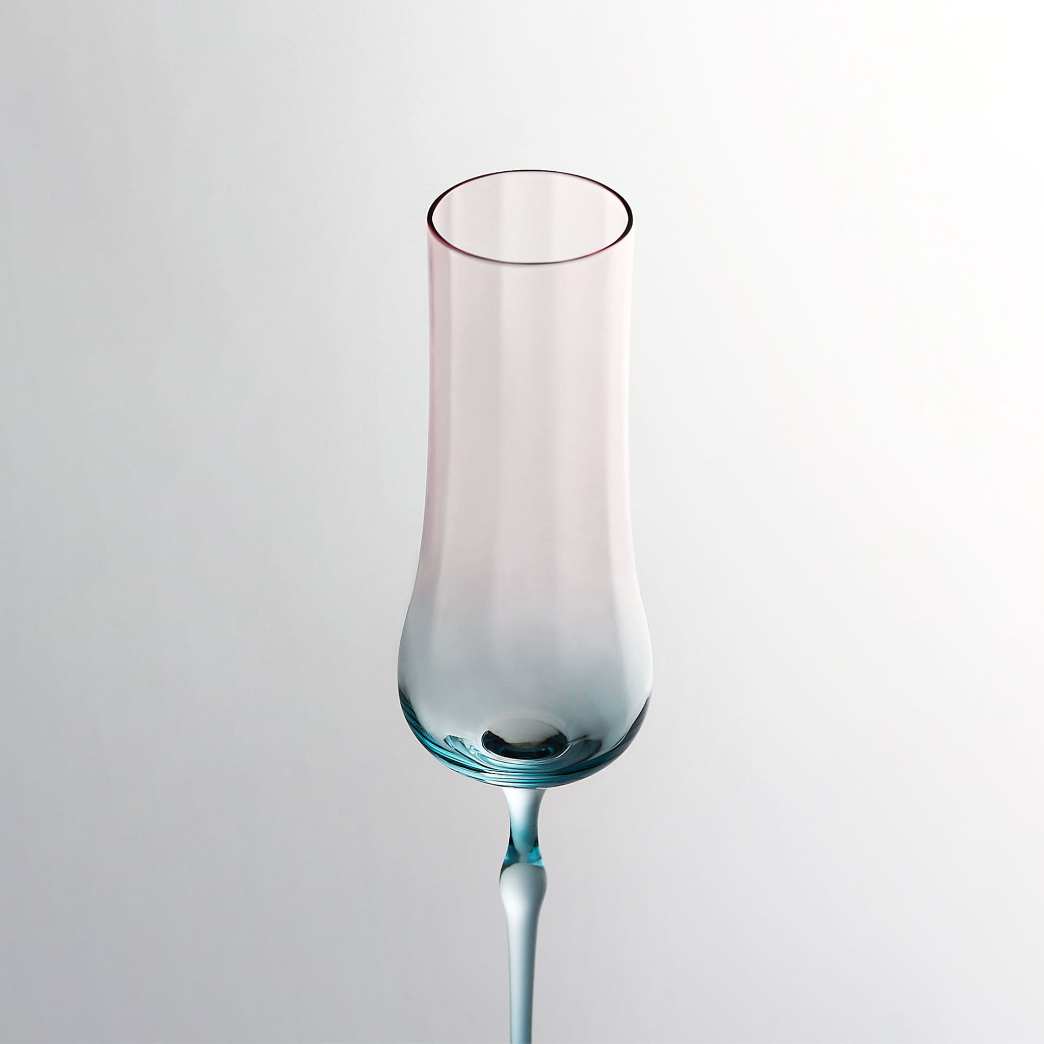 Close-up of crystal champagne glasses showing ribbed bowl texture, curved stems, and moon jellyfish-inspired color contrast