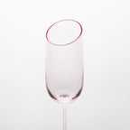 Close-up of crystal champagne glasses showing the angled rim, 4 mm stem, and soft pink glass detail