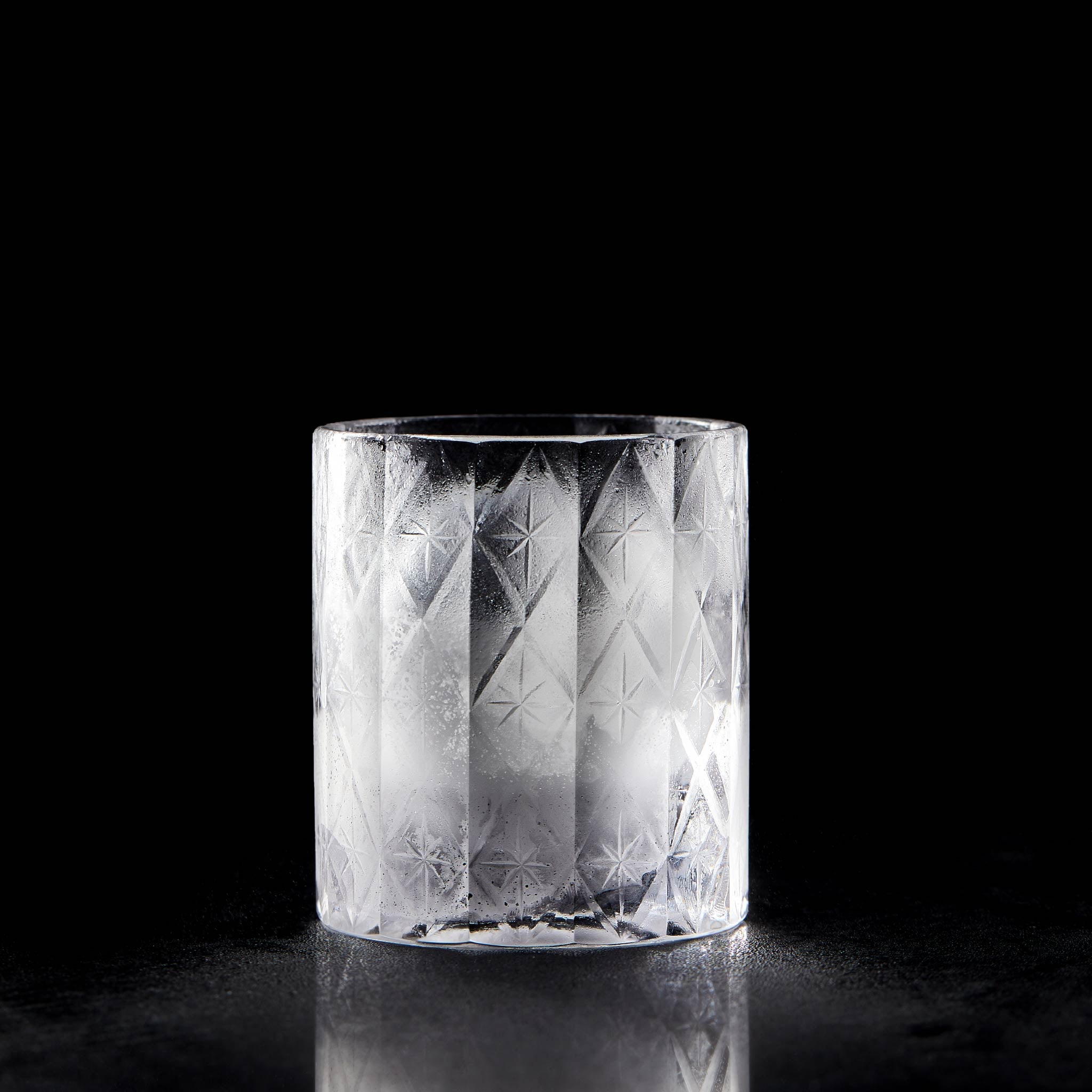 Close-up of crystal whiskey glass showing deep-cut texture, polished facets, and thick weighted base
