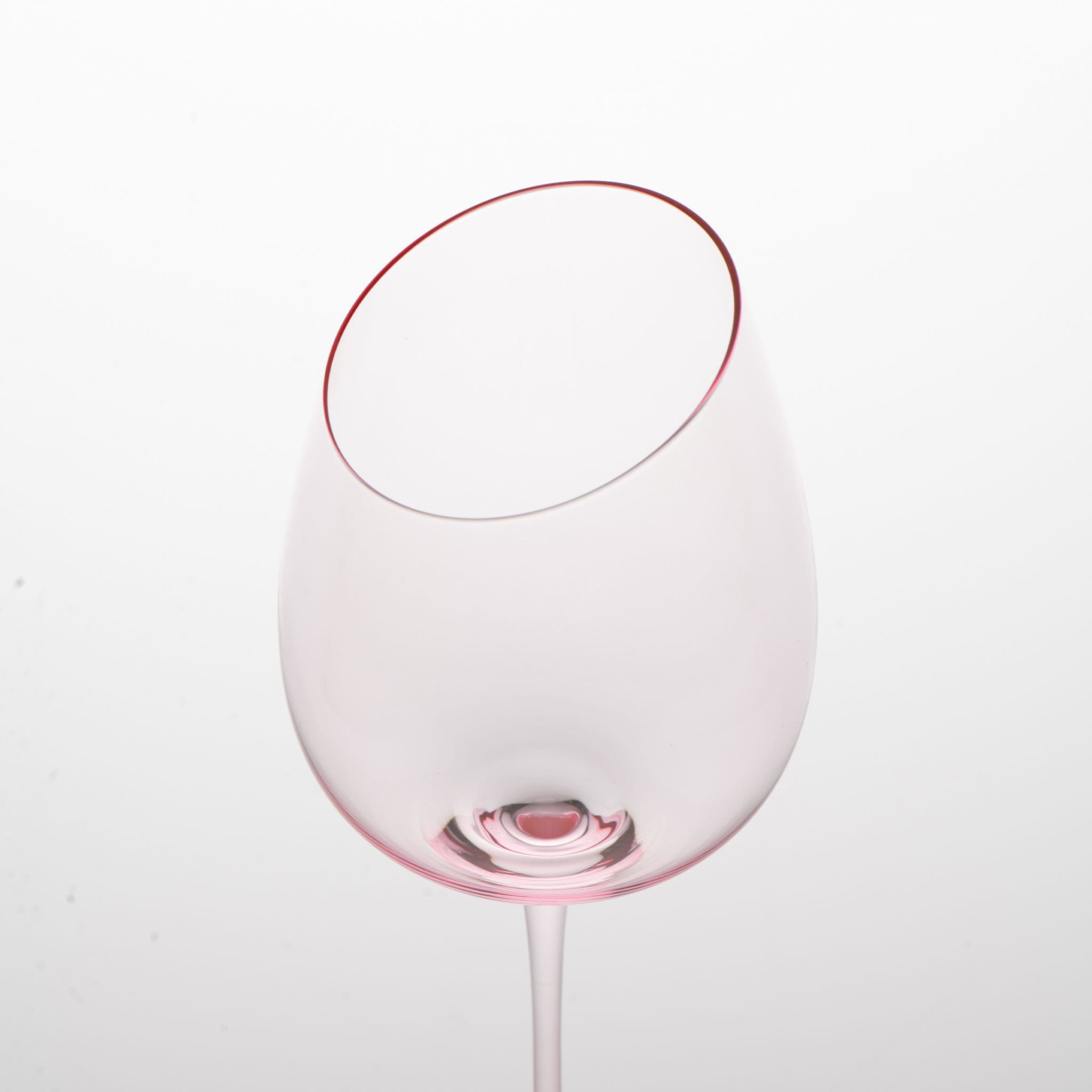 Close-up of crystal wine glasses showing the angled rim, 4 mm stem, and soft pink glass detail