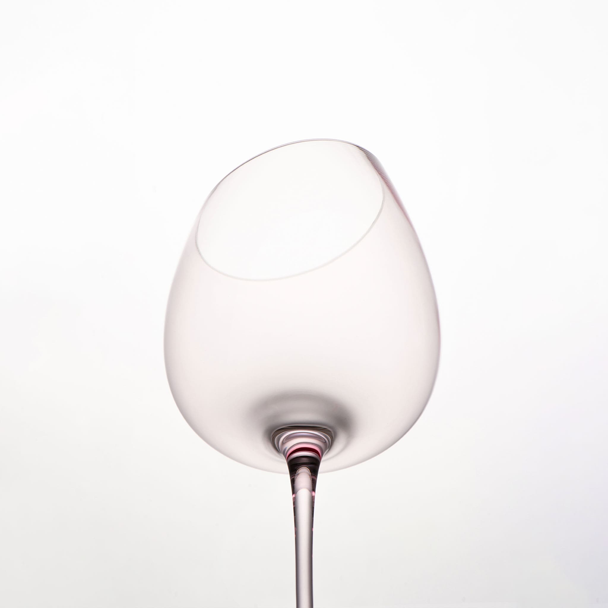 Close-up of crystal wine glasses showing the angled rim, 4 mm stem, and soft pink glass detail