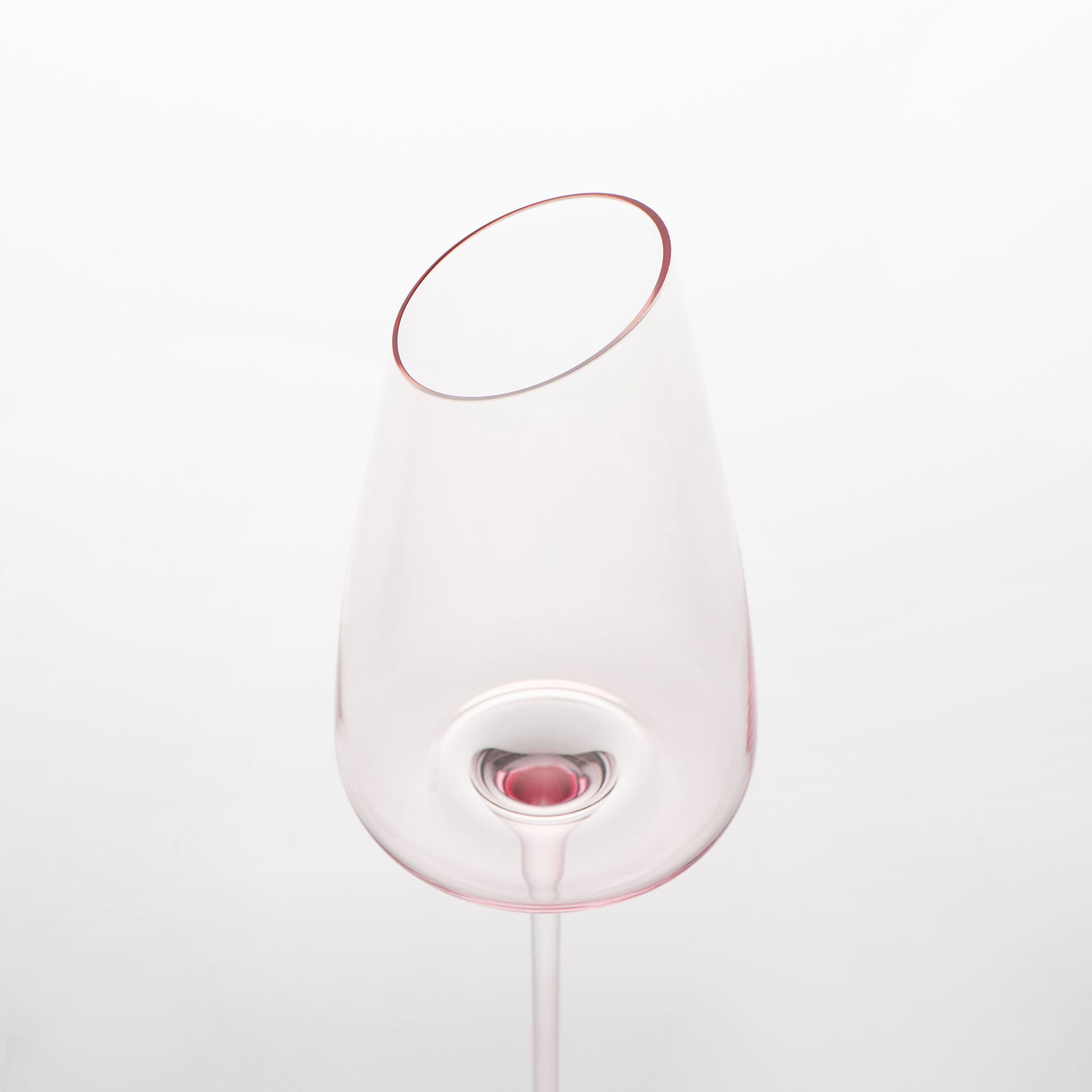 Close-up of crystal wine glasses showing the angled rim, 4 mm stem, and soft pink glass detail
