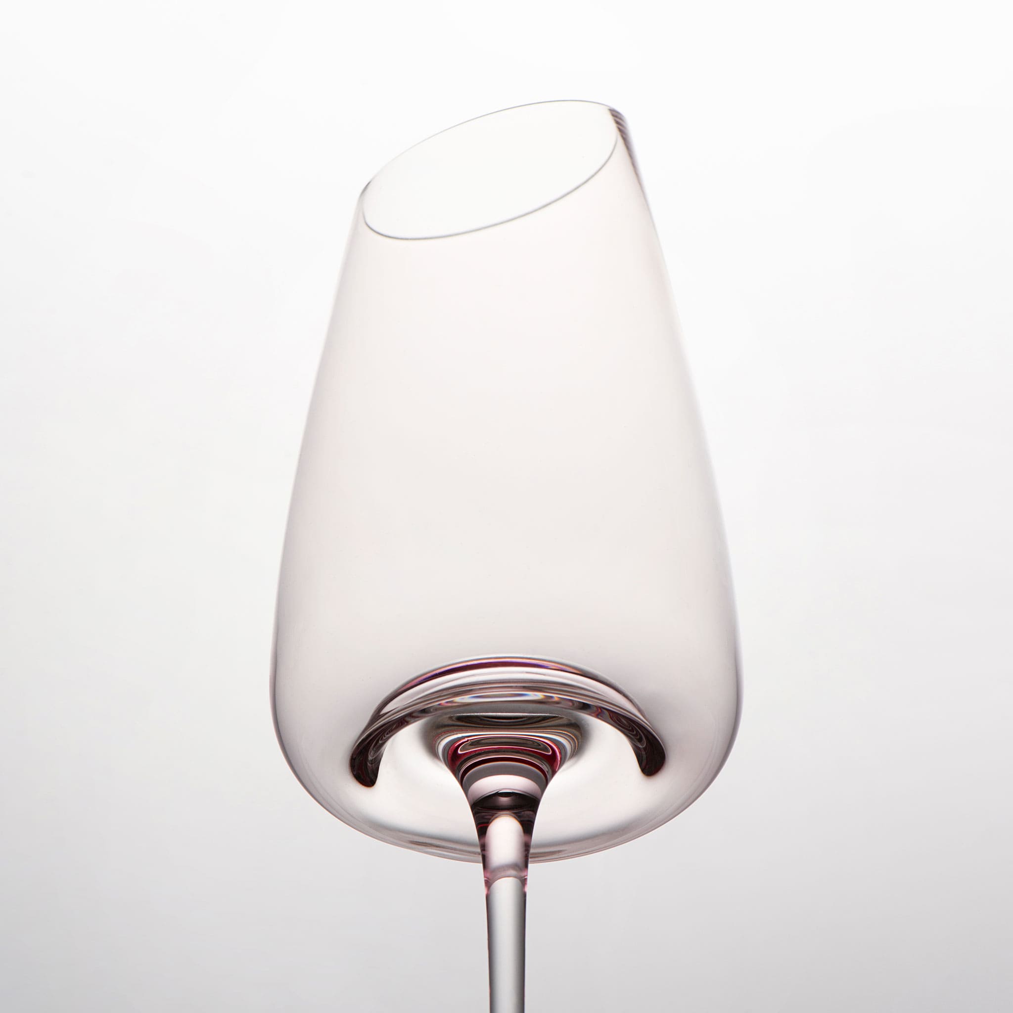 Close-up of crystal wine glasses showing the angled rim, 4 mm stem, and soft pink glass detail