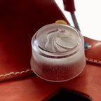 Clear plastic cap on a red leather surface