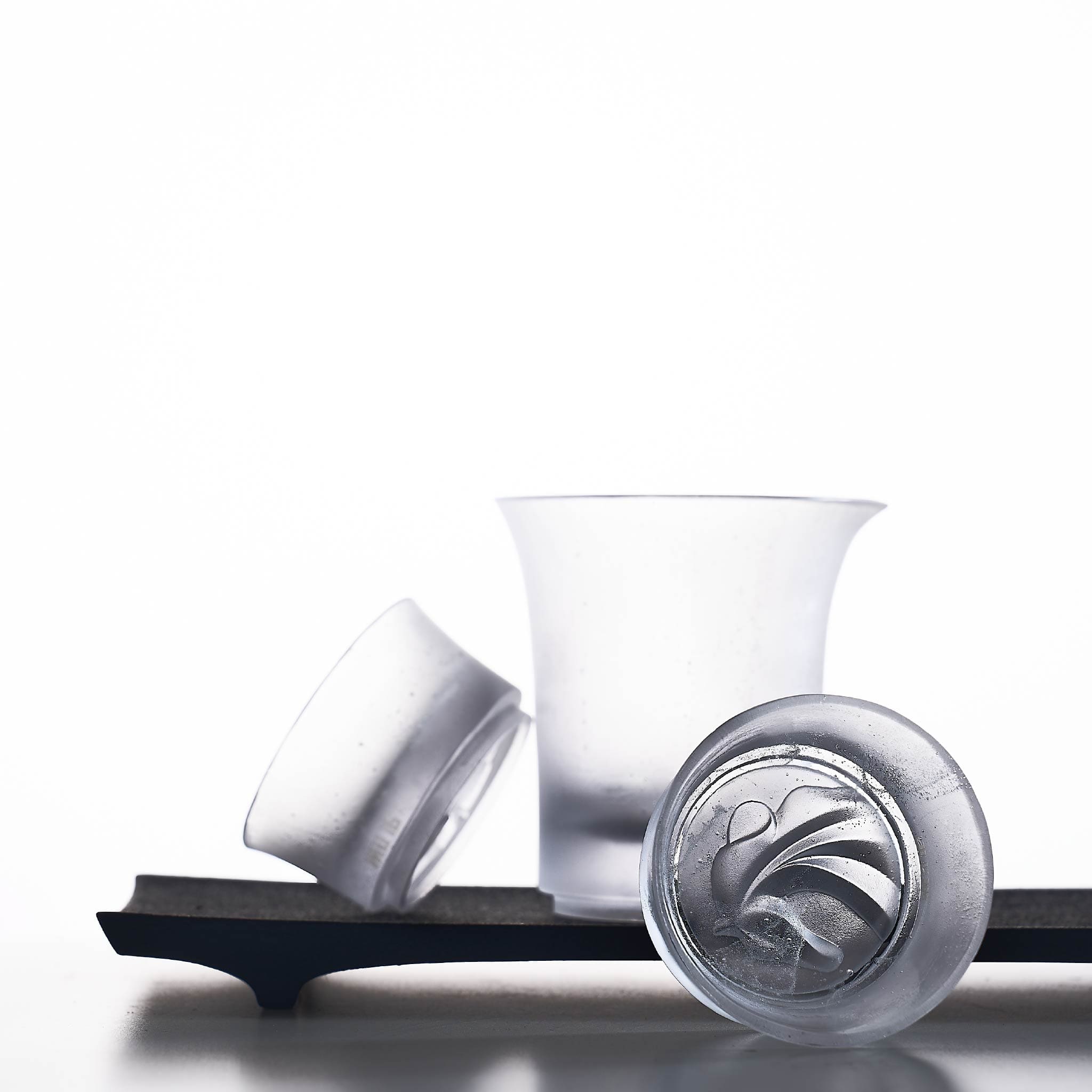 Three white containers with a black tray on a white background