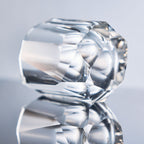 Close-up of crystal whiskey glass showing elongated gemstone-like facets, polished edges, and thick weighted base