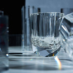 Close-up of crystal whiskey glass showing elongated gemstone-like facets, polished edges, and thick weighted base