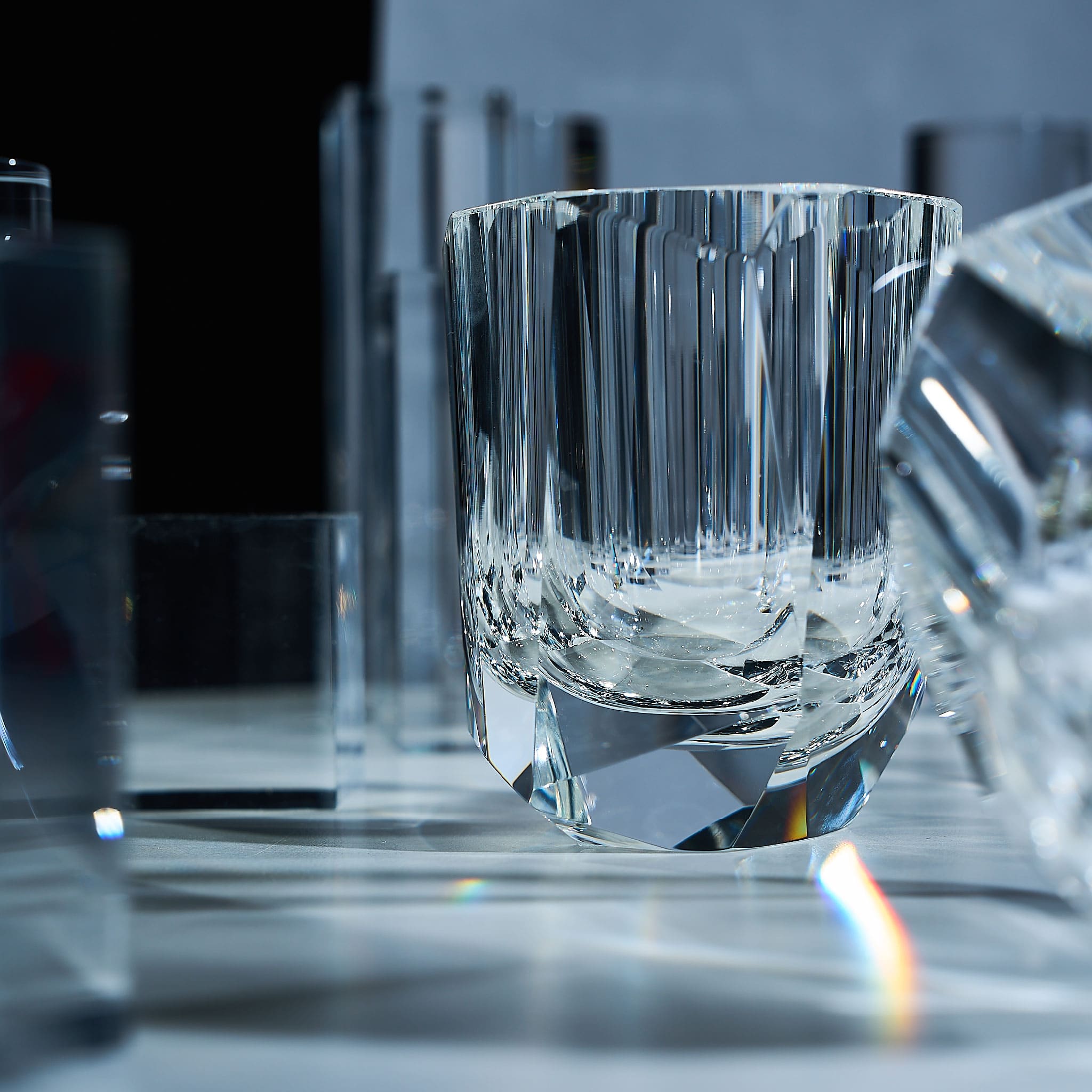 Close-up of crystal whiskey glass showing elongated gemstone-like facets, polished edges, and thick weighted base