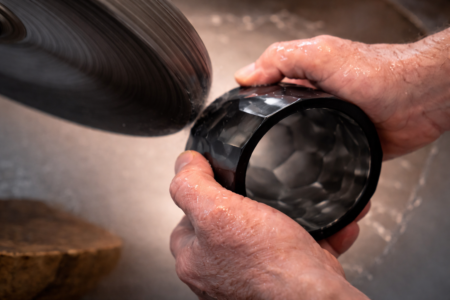 Close-up of crystal whiskey glass showing polygonal gemstone-like facets, polished edges, and thick weighted base