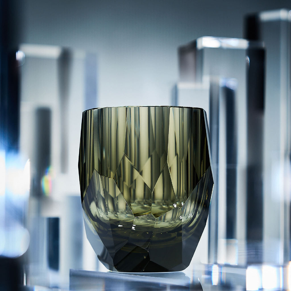 Close-up of crystal whiskey glass showing polygonal gemstone-like facets, polished edges, and thick weighted base