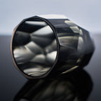 Close-up of crystal whiskey glass showing polygonal gemstone-like facets, polished edges, and thick weighted base