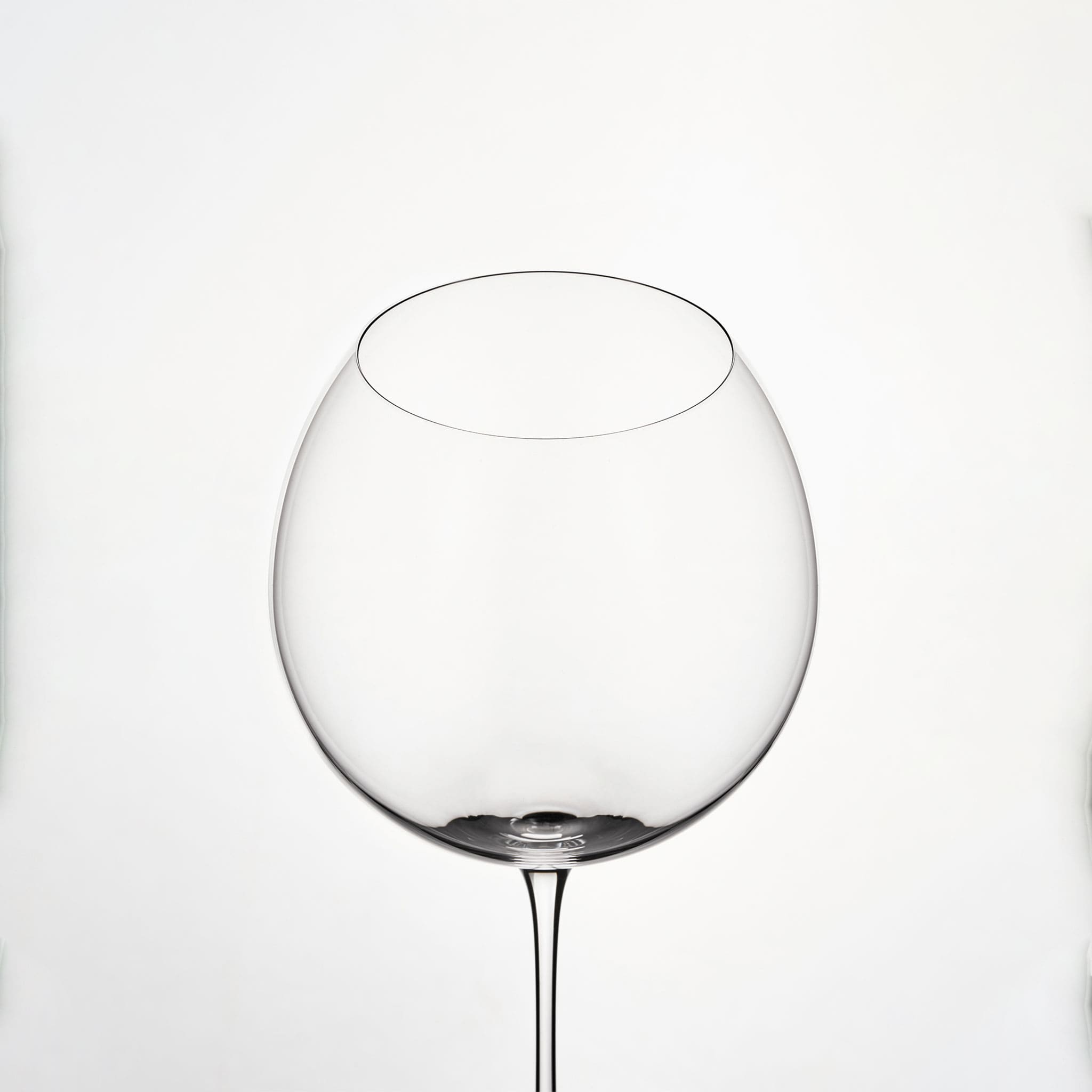 Close-up of hand-blown crystal wine glass showing ultra-thin rim, clear body, and refined stem detail